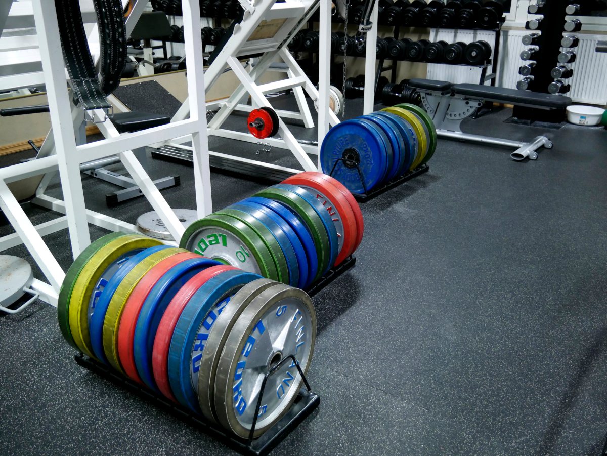 Discos de pesas de colores apilados en el suelo de un gimnasio.