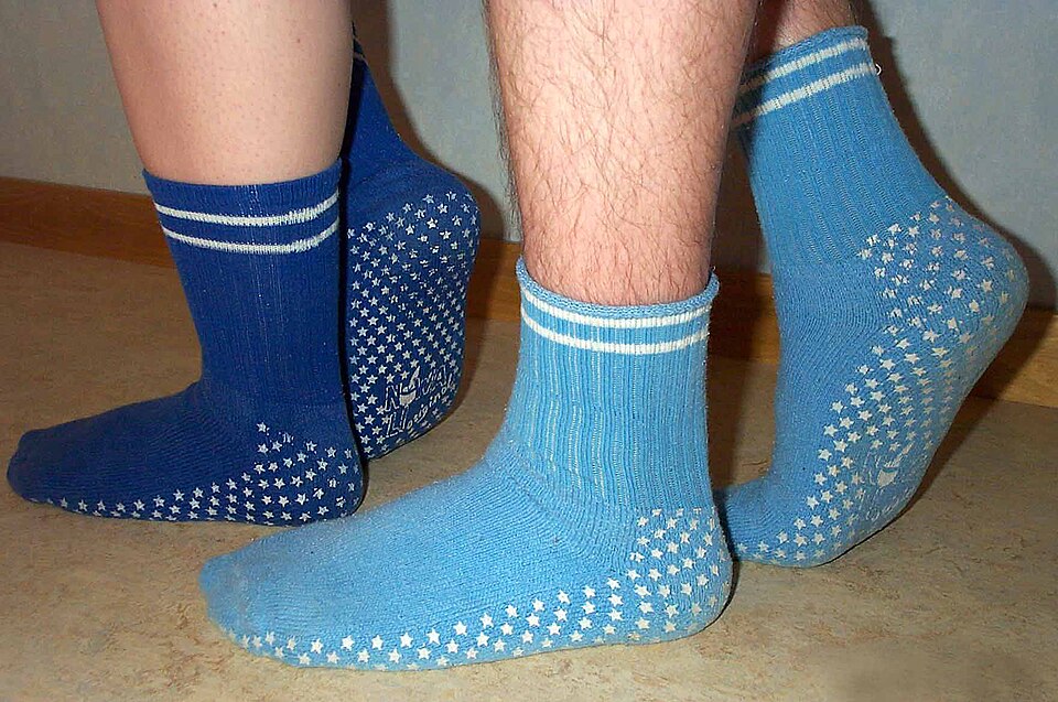 Dos pares de calcetines antideslizantes, uno azul oscuro y otro azul claro, con puntos blancos de agarre en la planta.